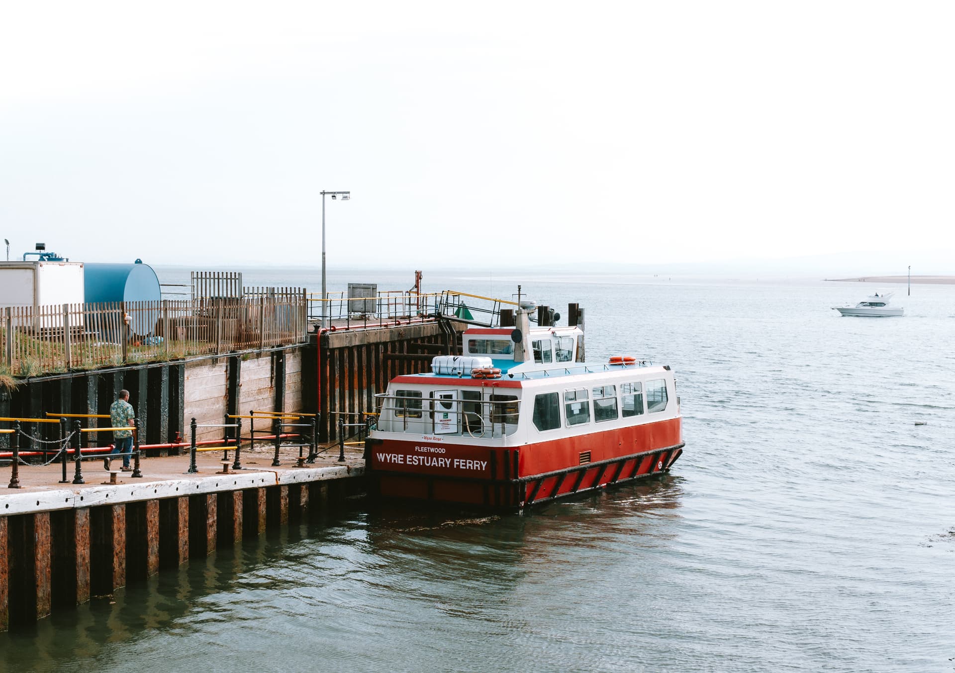 A serene coastal scene at a dock where the "Wyre Estuary Ferry" is moored. 